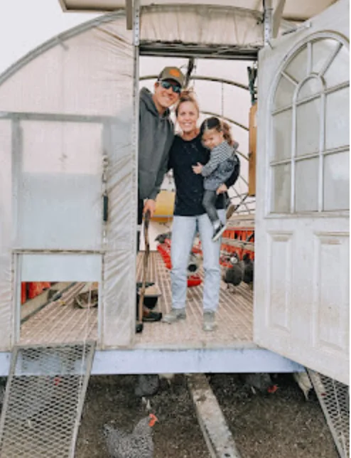 A family in the doorway of a chicken coop on the farm