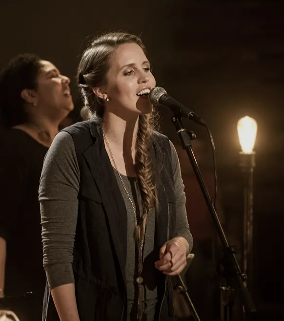 Jordyn singing at a microphone, leading worship